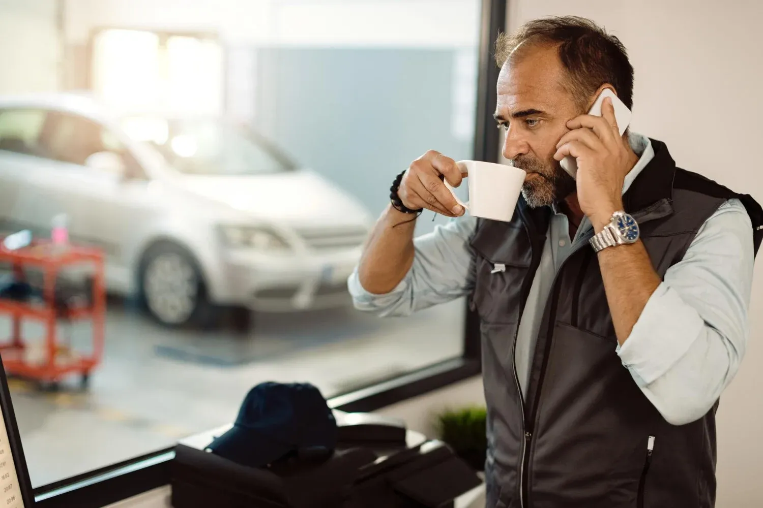 Car salesman drinking coffee and talking through the phone